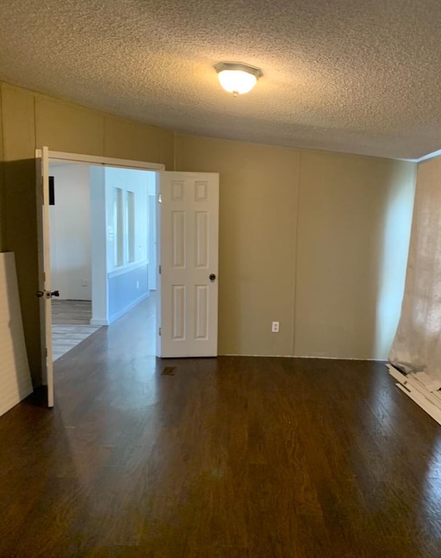 empty room with a textured ceiling and wood finished floors