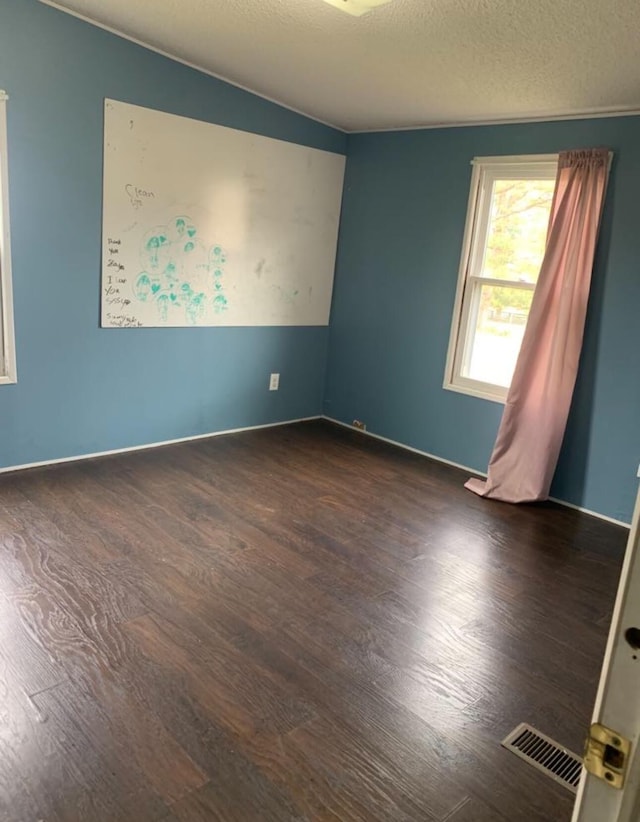 spare room featuring visible vents, dark wood finished floors, and a textured ceiling