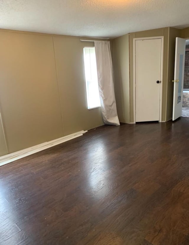 empty room with dark wood-style floors and a textured ceiling