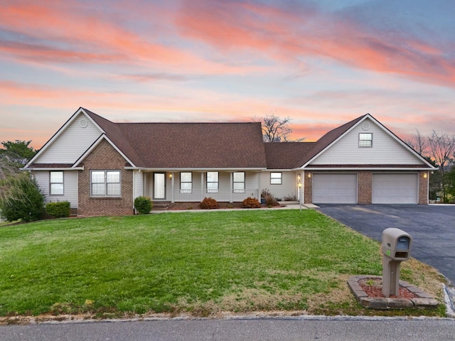 ranch-style house featuring aphalt driveway, brick siding, a garage, and a front lawn