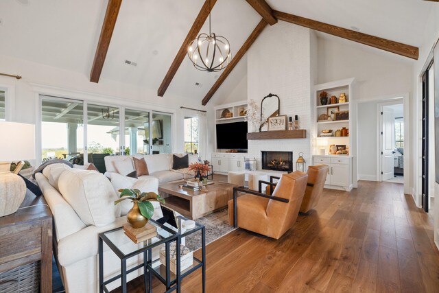 living room featuring high vaulted ceiling, a notable chandelier, visible vents, a brick fireplace, and hardwood / wood-style floors