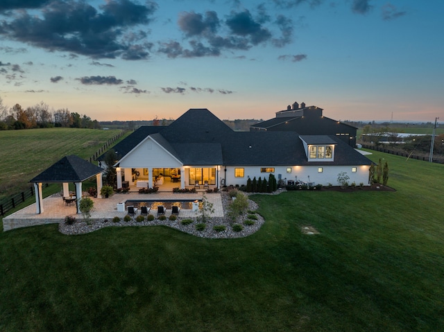 back of property at dusk with a patio area, a lawn, and a gazebo