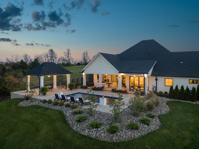 back of property at dusk with a gazebo, a lawn, a patio, and fence