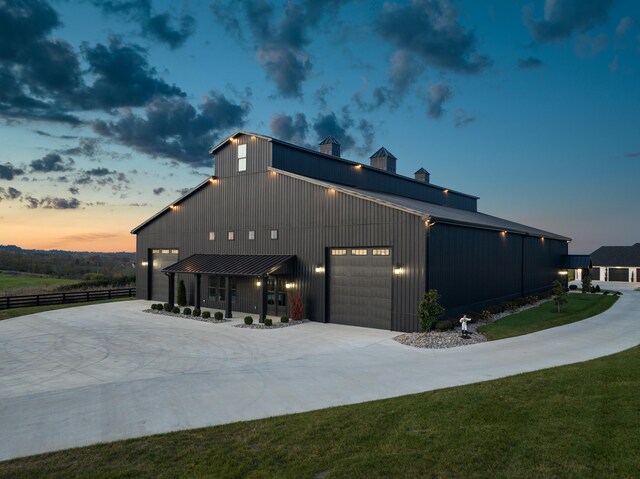 view of side of home featuring a garage, concrete driveway, metal roof, and a lawn