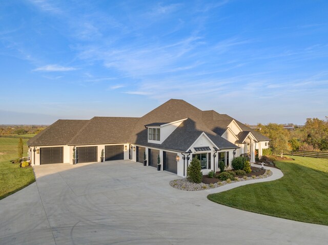 view of front facade featuring driveway, roof with shingles, an attached garage, fence, and a front yard