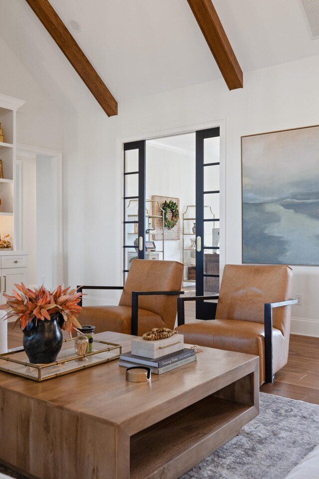 living area with lofted ceiling with beams, french doors, wood finished floors, and visible vents