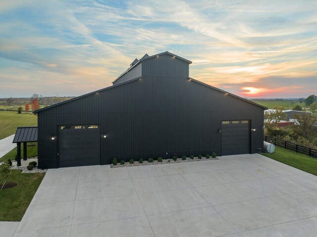 view of side of property with driveway, a lawn, a detached garage, and fence