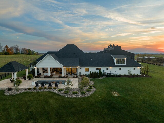 back of property at dusk with a patio, a lawn, and outdoor lounge area