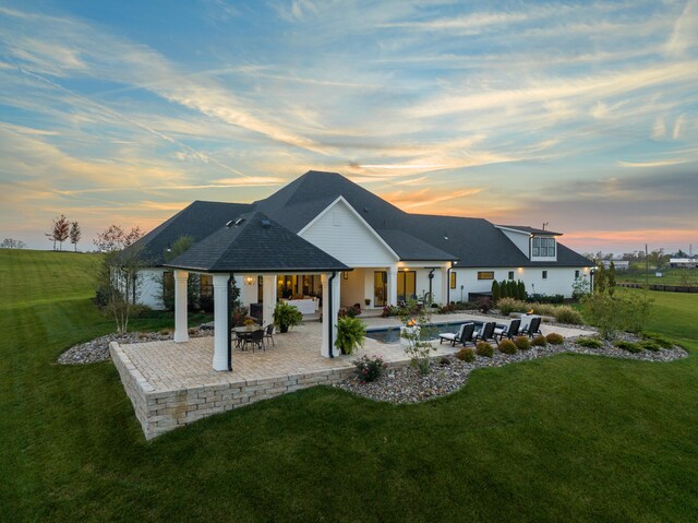 back of property at dusk featuring a patio area and a yard