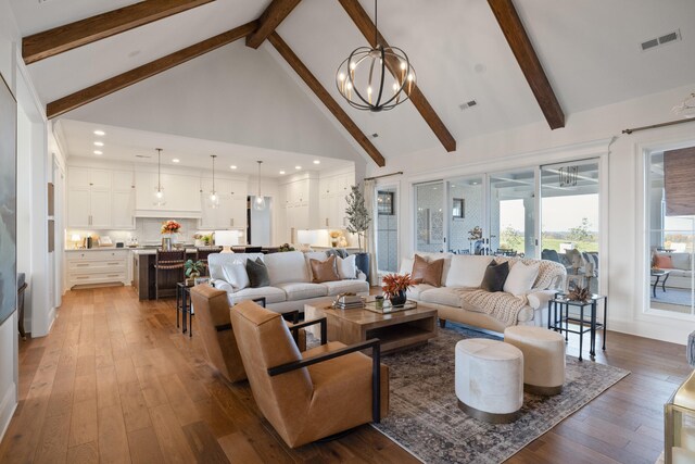 living room featuring a chandelier, visible vents, light wood-style floors, and high vaulted ceiling