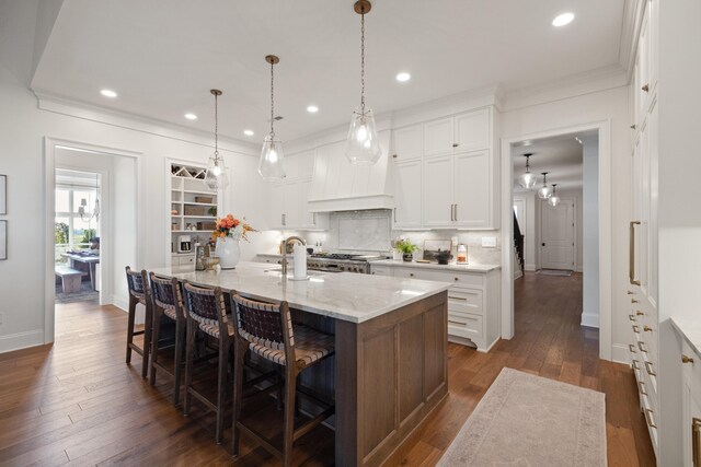 kitchen with a breakfast bar, decorative backsplash, ornamental molding, dark wood-type flooring, and a sink