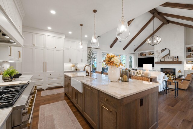 kitchen featuring dark wood-style floors, a fireplace, a sink, and range hood