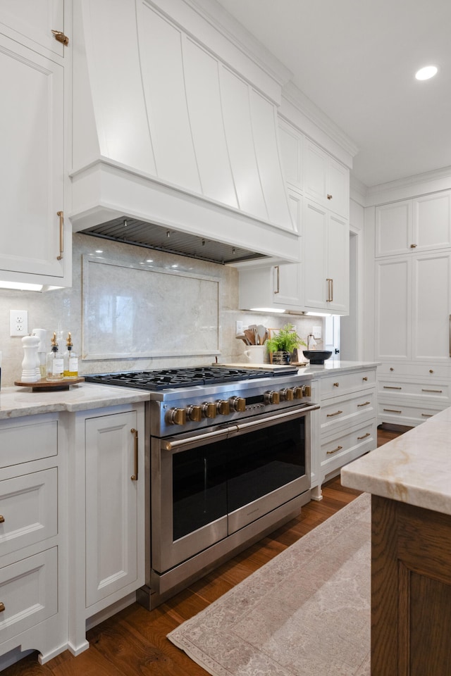 kitchen with double oven range, white cabinetry, dark wood finished floors, and premium range hood