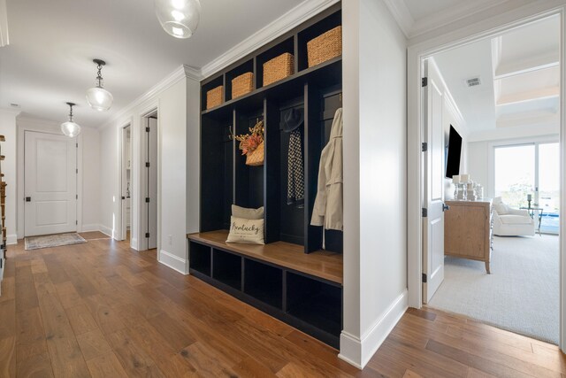 mudroom with ornamental molding, wood-type flooring, visible vents, and baseboards