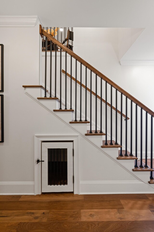 staircase featuring crown molding, baseboards, and wood finished floors