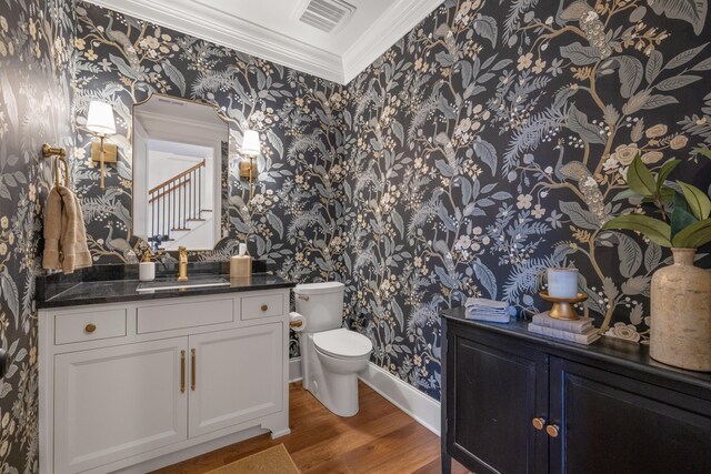 half bath with wallpapered walls, visible vents, toilet, wood finished floors, and vanity