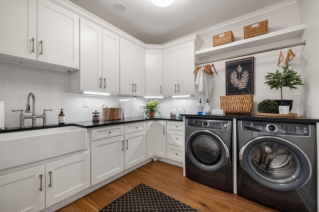 laundry room with cabinet space, wood finished floors, crown molding, separate washer and dryer, and a sink