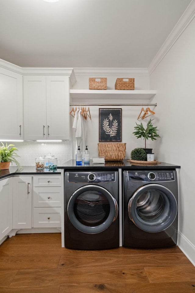 laundry area with ornamental molding, cabinet space, light wood-style flooring, and separate washer and dryer