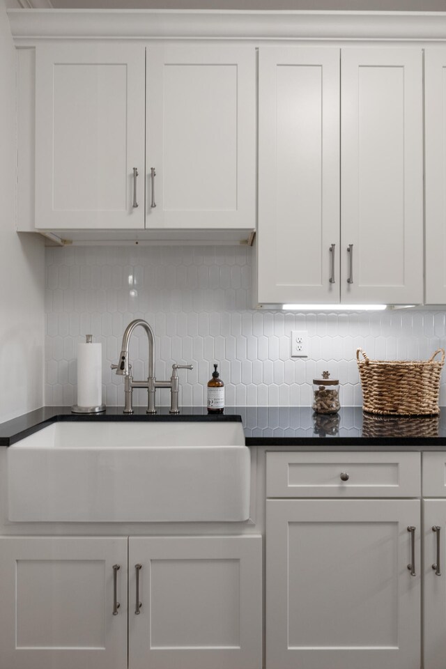 kitchen with dark countertops, white cabinetry, and a sink