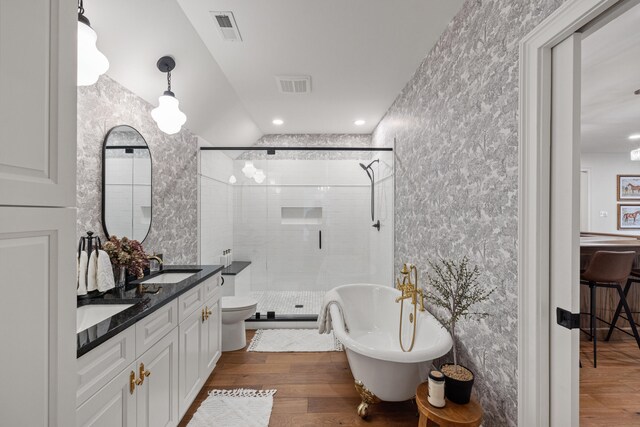 bathroom with a sink, a stall shower, wood finished floors, and visible vents