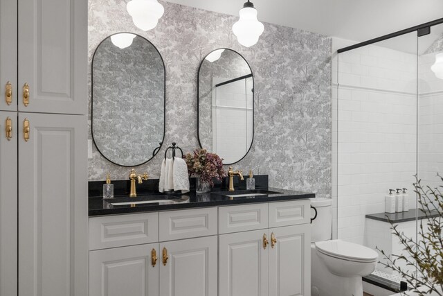 bathroom featuring double vanity, a stall shower, toilet, and a sink