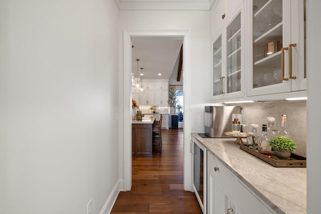 bar featuring dark wood-type flooring, wine cooler, backsplash, and baseboards