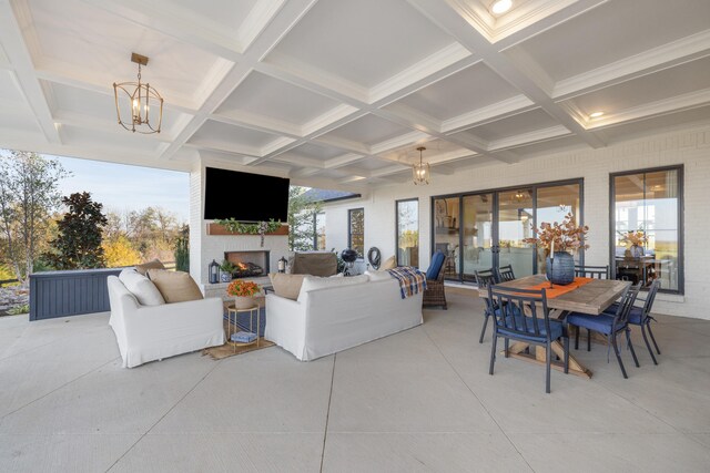 living room with a warm lit fireplace, beamed ceiling, coffered ceiling, and a wealth of natural light