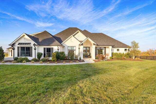 modern farmhouse featuring a shingled roof, fence, and a front lawn