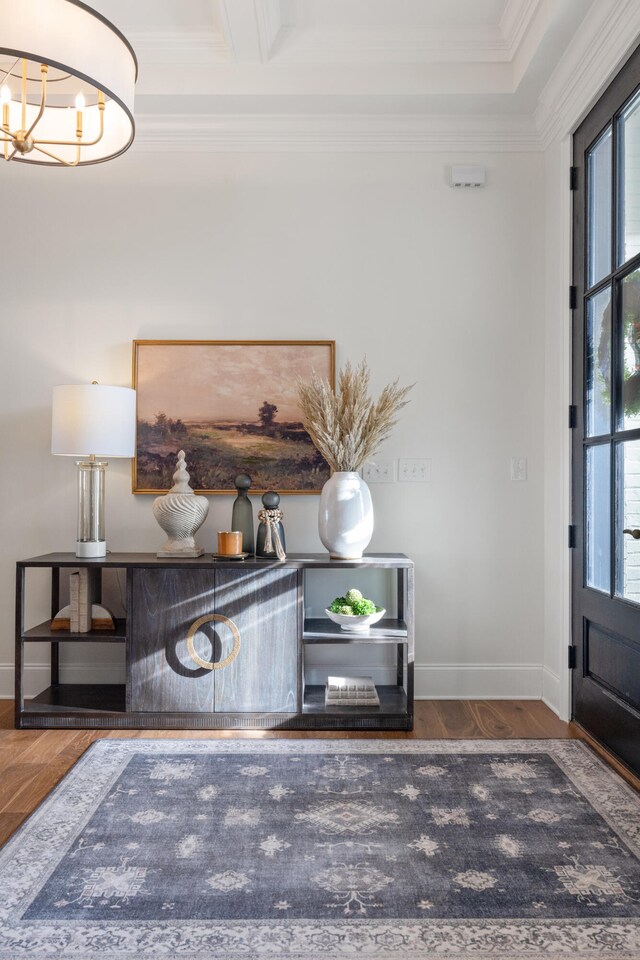 foyer entrance featuring ornamental molding, a chandelier, baseboards, and wood finished floors