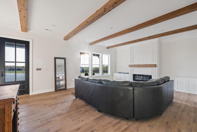 living room with beam ceiling, visible vents, a glass covered fireplace, light wood-type flooring, and baseboards