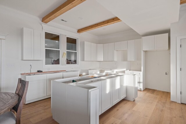 kitchen featuring light wood-type flooring, a kitchen island, white cabinetry, and beam ceiling