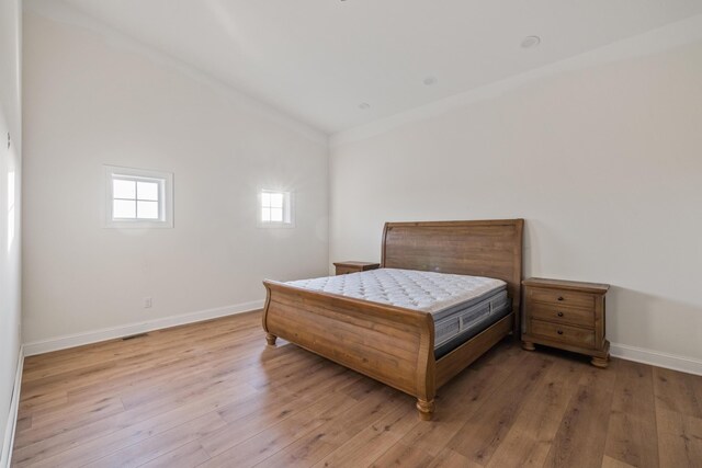 bedroom featuring light wood-style flooring, baseboards, and vaulted ceiling