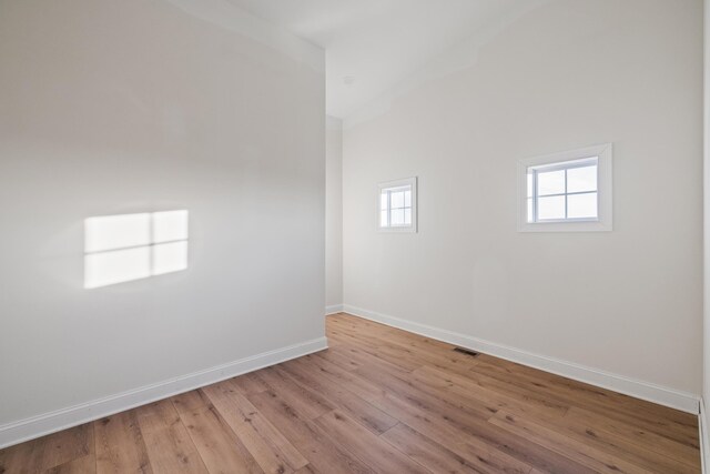 empty room with light wood-type flooring, visible vents, and baseboards