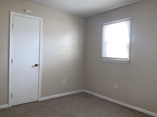 spare room featuring carpet and baseboards