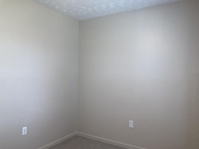 carpeted empty room featuring baseboards and a textured ceiling