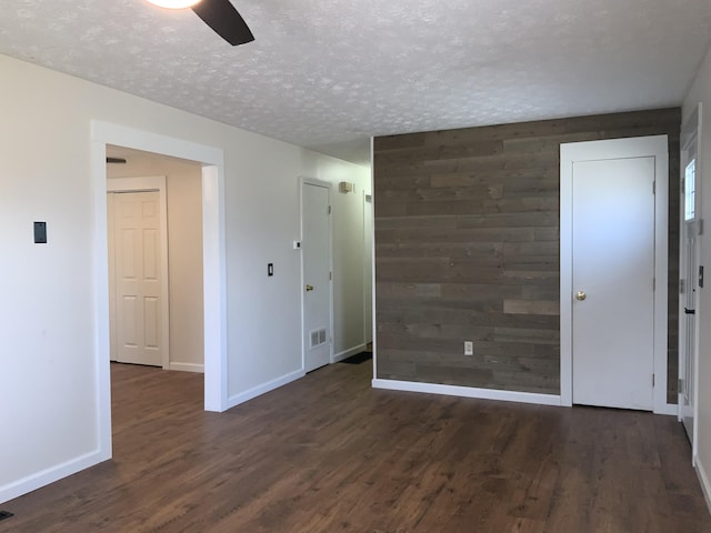 spare room with a textured ceiling, wood walls, and wood finished floors