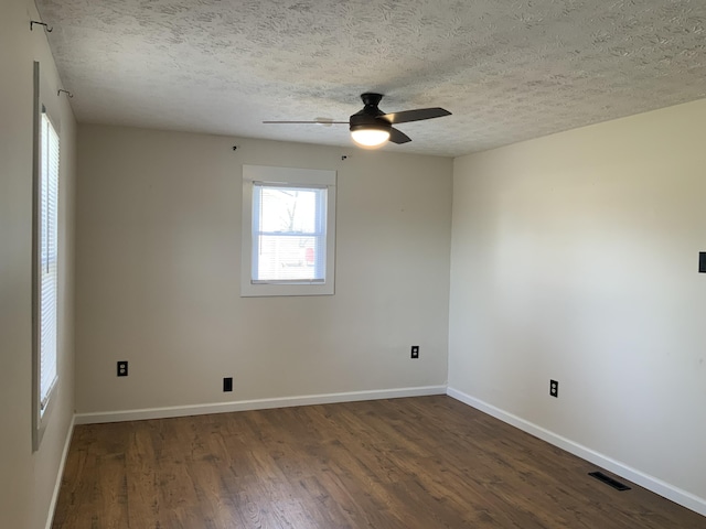 empty room with a textured ceiling, ceiling fan, wood finished floors, visible vents, and baseboards