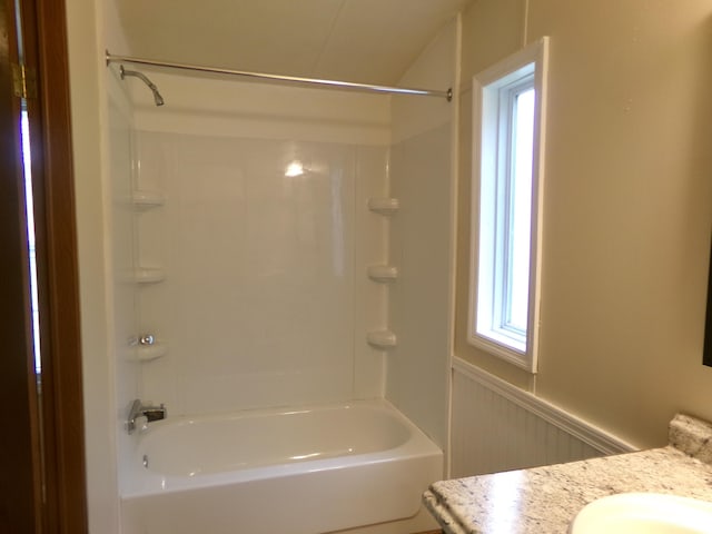 bathroom featuring wainscoting, bathing tub / shower combination, and vanity