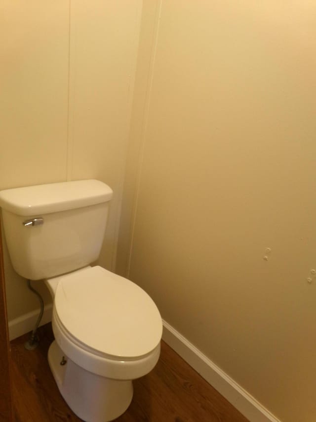 bathroom with toilet, baseboards, and wood finished floors