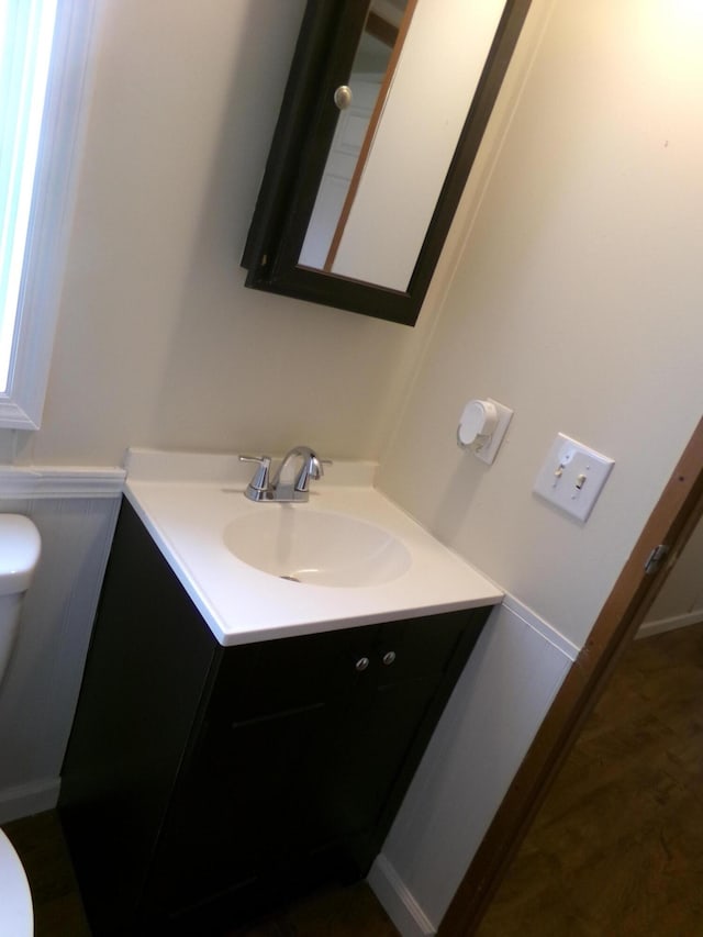 bathroom with a wainscoted wall, vanity, and toilet