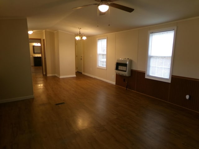 spare room with visible vents, wainscoting, dark wood-style flooring, heating unit, and ceiling fan with notable chandelier