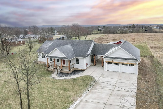 view of front of home with concrete driveway, roof with shingles, an attached garage, a yard, and a porch