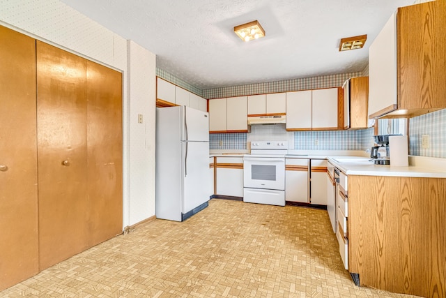 kitchen with white appliances, tasteful backsplash, light countertops, under cabinet range hood, and a sink