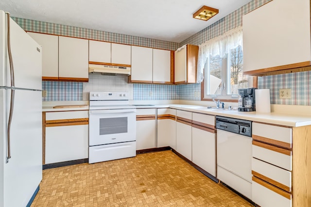 kitchen featuring white appliances, light countertops, a sink, and under cabinet range hood