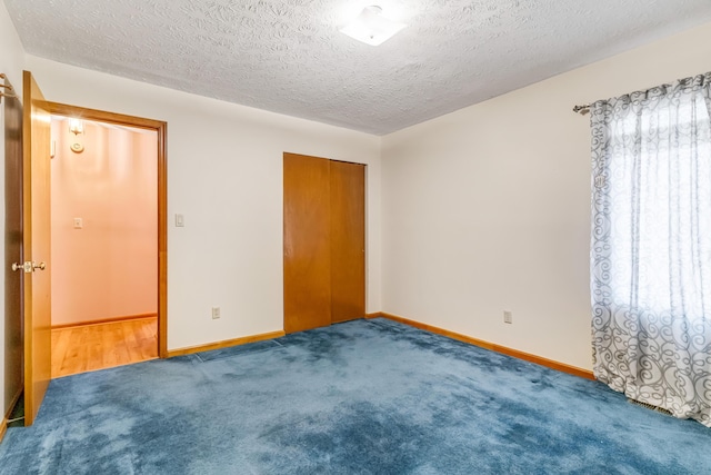 empty room featuring carpet floors, baseboards, and a textured ceiling