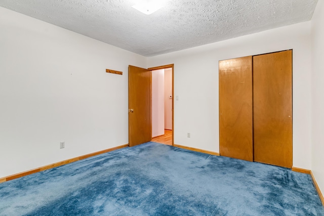 unfurnished bedroom with a textured ceiling, a closet, and baseboards