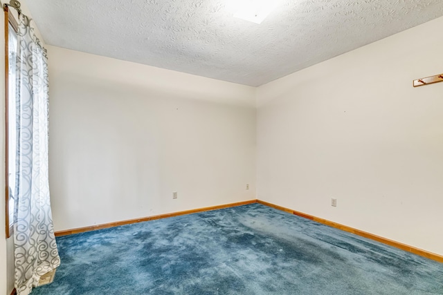 carpeted spare room with baseboards and a textured ceiling