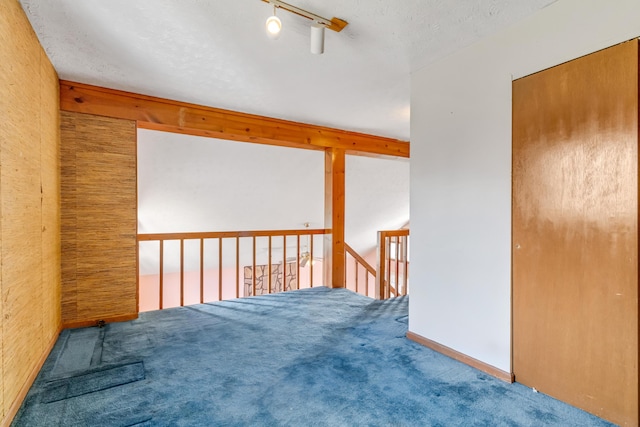 unfurnished bedroom with a textured ceiling, carpet flooring, and rail lighting