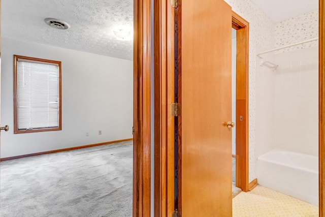 hall with carpet, baseboards, visible vents, and a textured ceiling