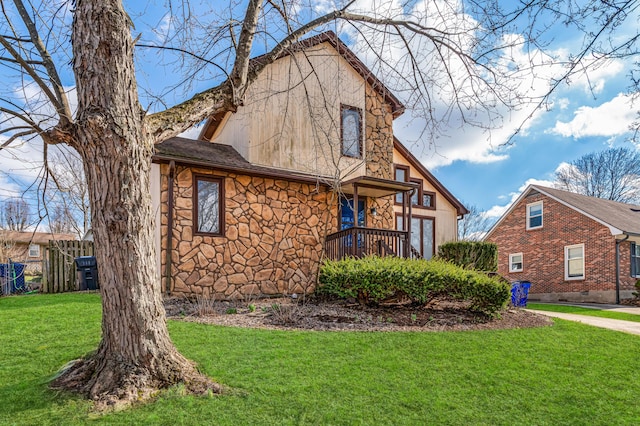 view of front of house with stone siding, fence, and a front lawn